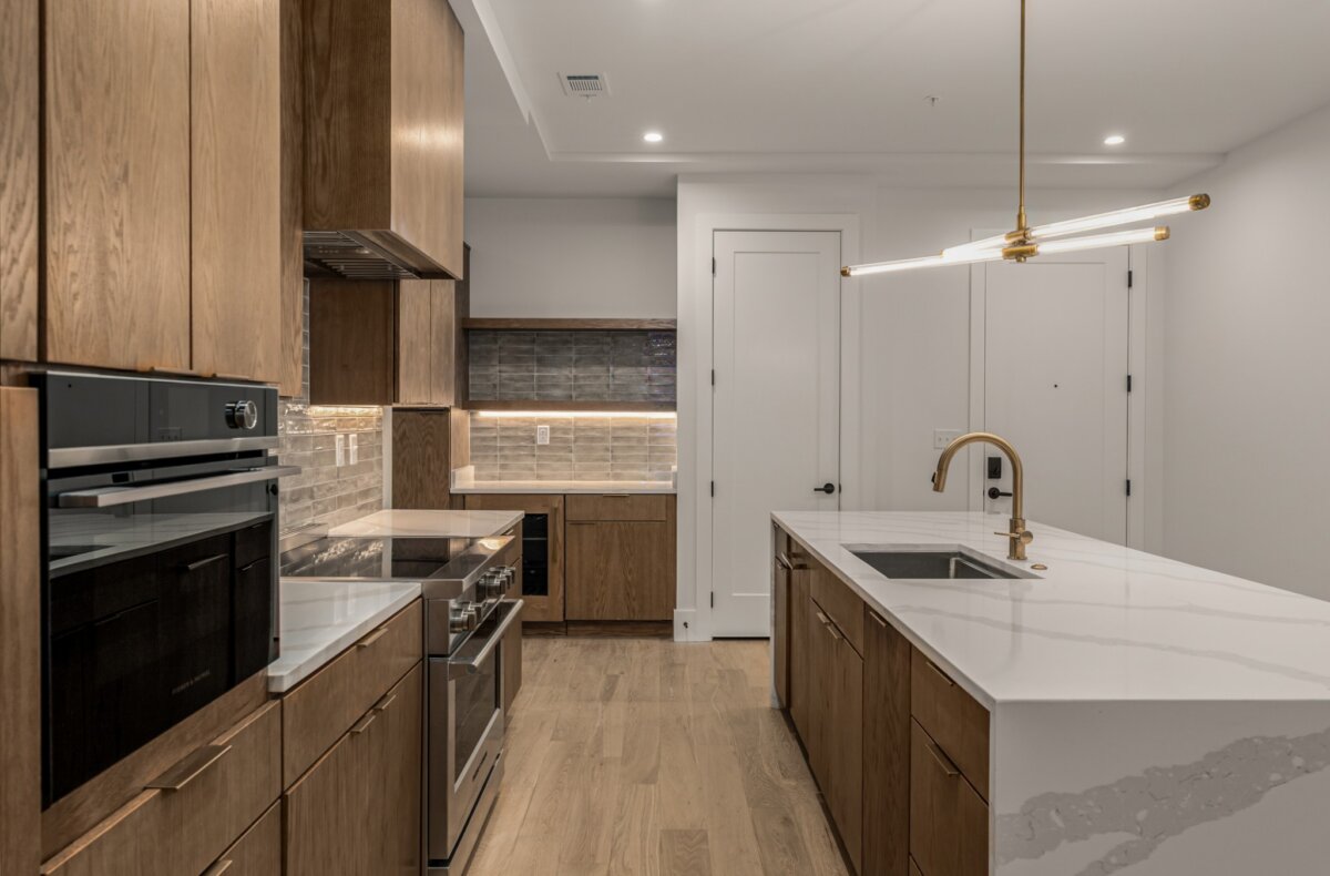 Modern kitchen with wooden cabinets, stainless steel appliances, marble countertop island, built-in oven, subway tile backsplash, and pendant lighting—perfectly designed for contemporary living at 321 31st Ave N, Nashville TN.