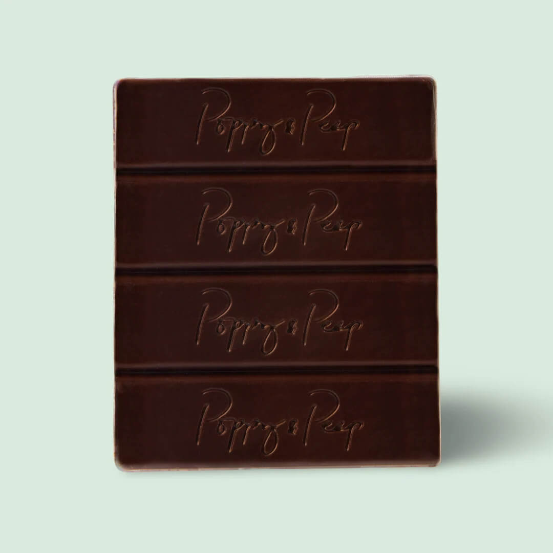 10 Grown-Up Halloween Candies We’re Keeping for Ourselves - 8 A rectangular dark chocolate bar divided into four sections, each embossed with the words “Poppy & Peep,” on a light gray background—a sophisticated treat perfect for any gourmet candy guide or for those seeking grown-up Halloween candy options.