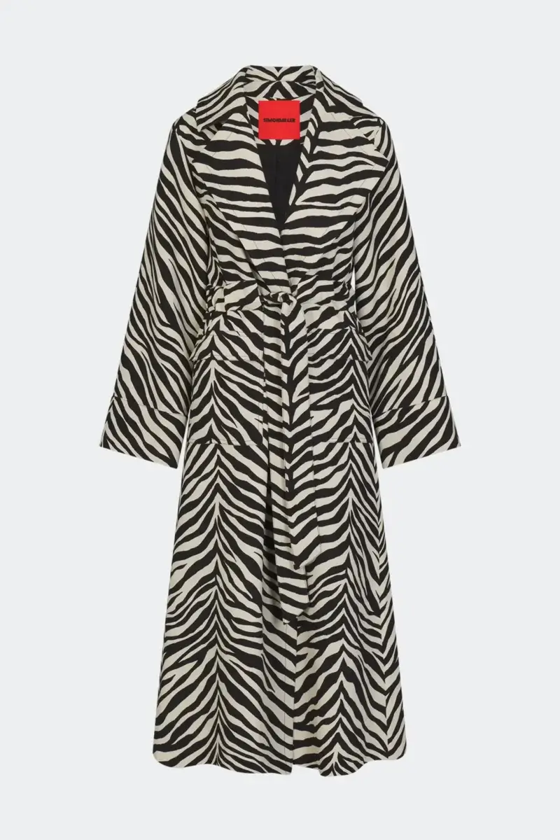 Fall Is Getting Wild: Animal Prints Are Back! - 9 A long, belted trench coat with black and white zebra stripes—embracing bold animal prints—displayed on a plain white background. This striking piece makes an effortless statement for fall fashion.