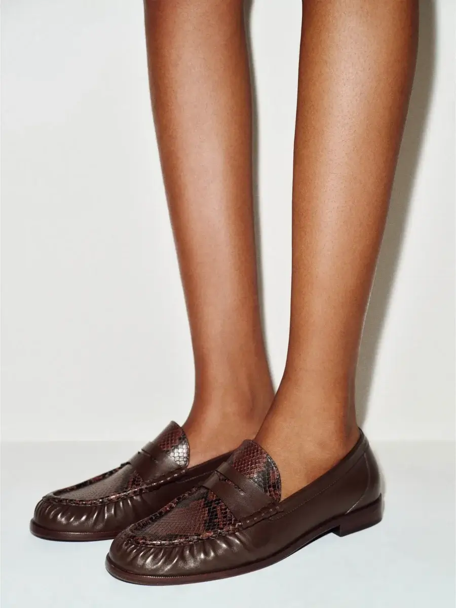 Fall Is Getting Wild: Animal Prints Are Back! - 18 A person wearing brown leather loafers with a textured pattern, standing against a plain light background—a perfect nod to autumn trends and fall fashion.