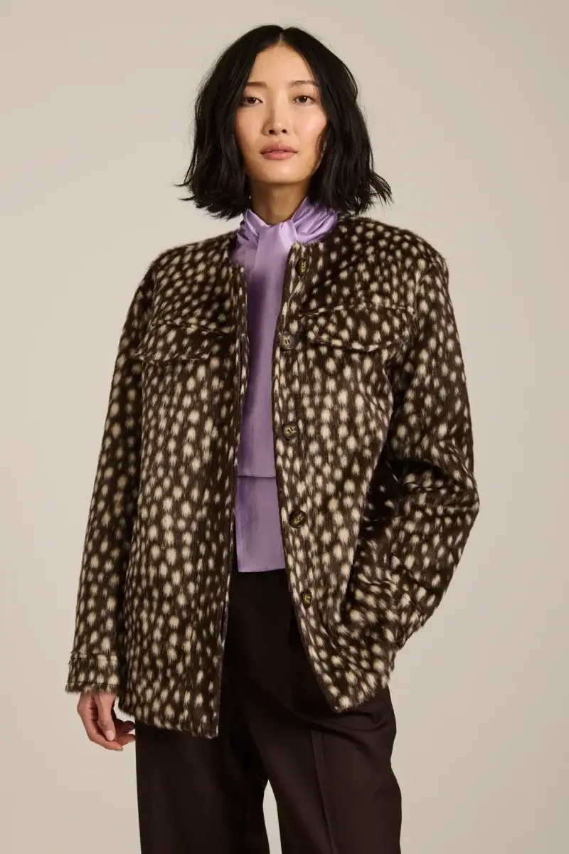 Fall Is Getting Wild: Animal Prints Are Back! - 11 Woman wearing a stylish brown and white animal print jacket over a purple blouse and dark pants, standing against a plain background—a perfect look for fall fashion.