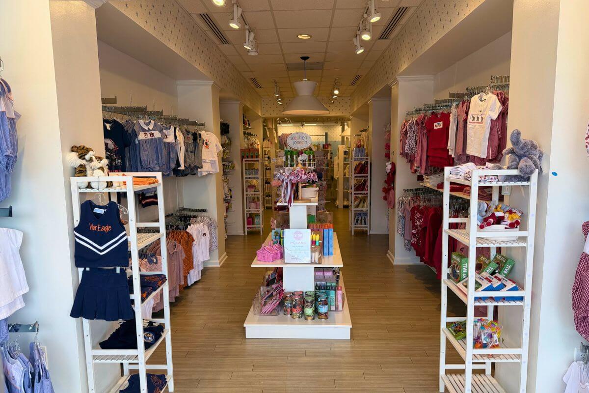 Children’s clothing and gift shop, Lili Pad, with racks of clothes on both sides, shelves of toys and accessories, and bright lighting throughout the store.