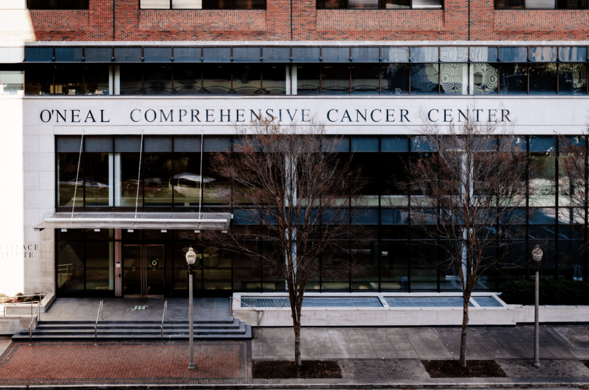This BHAM Doctor Fights for Women's Lives Every Day - 4 Exterior view of the O’Neal Comprehensive Cancer Center building, showing its main entrance, large windows, and bare trees lining the sidewalk—a hub for research and advocacy dedicated to improving women’s lives under the leadership of renowned BHAM doctors.