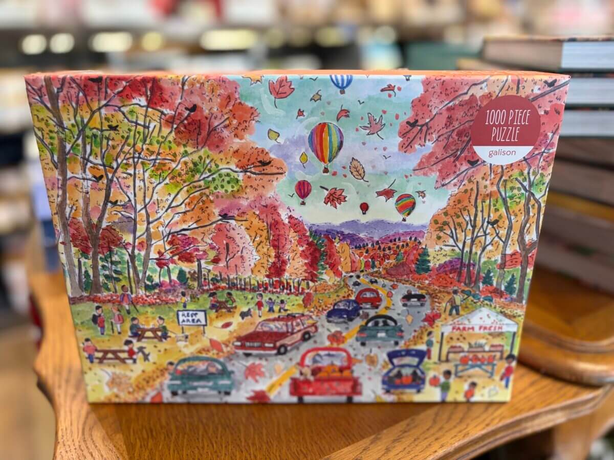 A 1000-piece puzzle box featuring a colorful autumn scene with cars, trees, hot air balloons, and a roadside market—perfect for adding a touch of fall decor to your home.