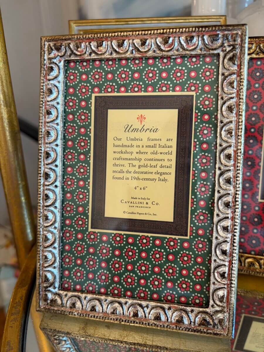 Ornate picture frame with a patterned border and a label describing the handmade Umbria frame, crafted in Italy with gold-leaf detail, inspired by 19th-century Italian design—an elegant piece perfect for elevating your fall decor.