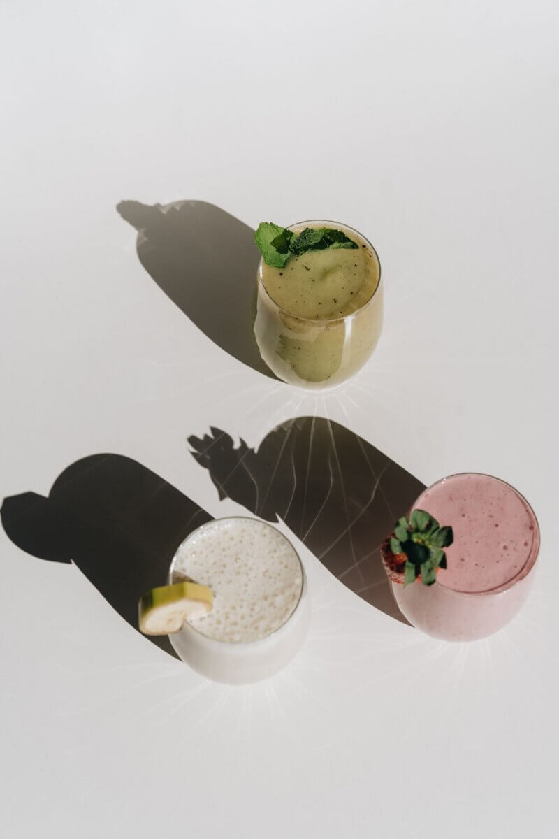 Pumpkin Is Not Just for Lattes — Supercharge Your Fall Smoothies and Salads! - 2 Three glasses of smoothies—green with mint, white with lemon, and pink with strawberry—are arranged on a white surface, perfect for enjoying refreshing fall smoothies.