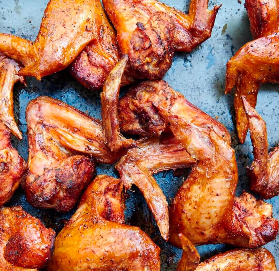 Several baked chicken wings are spread out on a dark metal baking sheet, seasoned with spices and cooked to a golden brown—a delicious dish you might find at some of the best Birmingham restaurants.