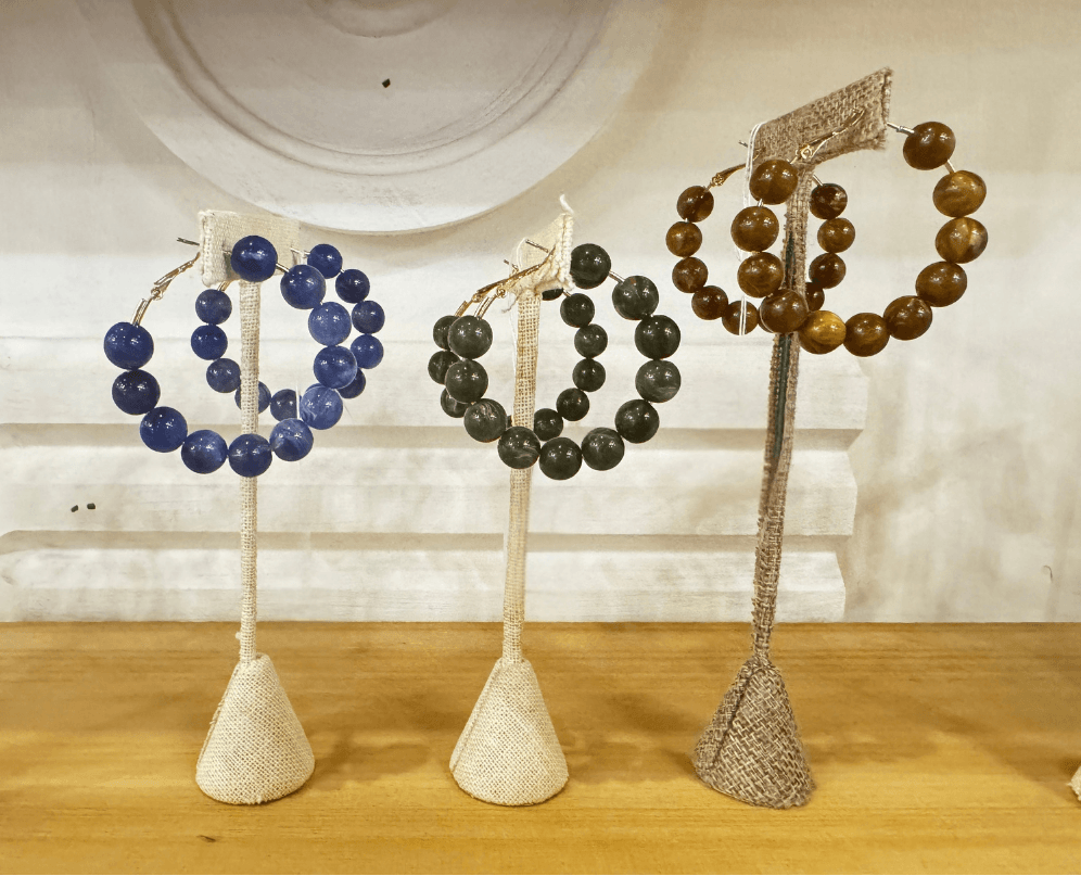 17 Louisville FINDS for October: Fall Fashion, Festive Decor & Game-Day Essentials - 6 Three beaded earring pairs—blue, green, and brown—are displayed upright on fabric-covered stands against a light-colored background, showcasing unique October FINDS from Louisville.