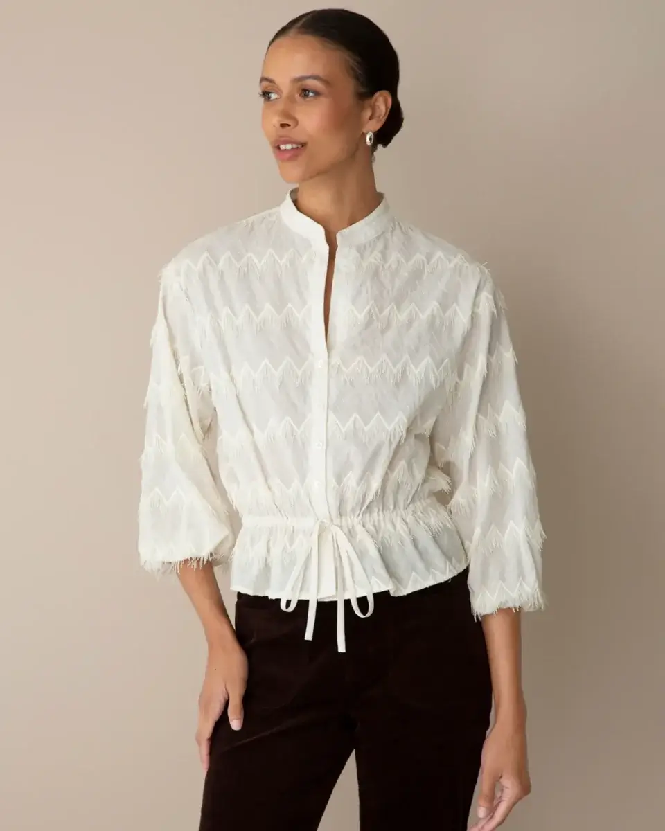 17 Fall-Ready Nashville FINDS: Cozy Layers, Beauty & Spooky Season Style - 3 Woman wearing a white textured blouse with mandarin collar and drawstring waist, paired with dark pants—an elegant look among our Nashville finds this October.