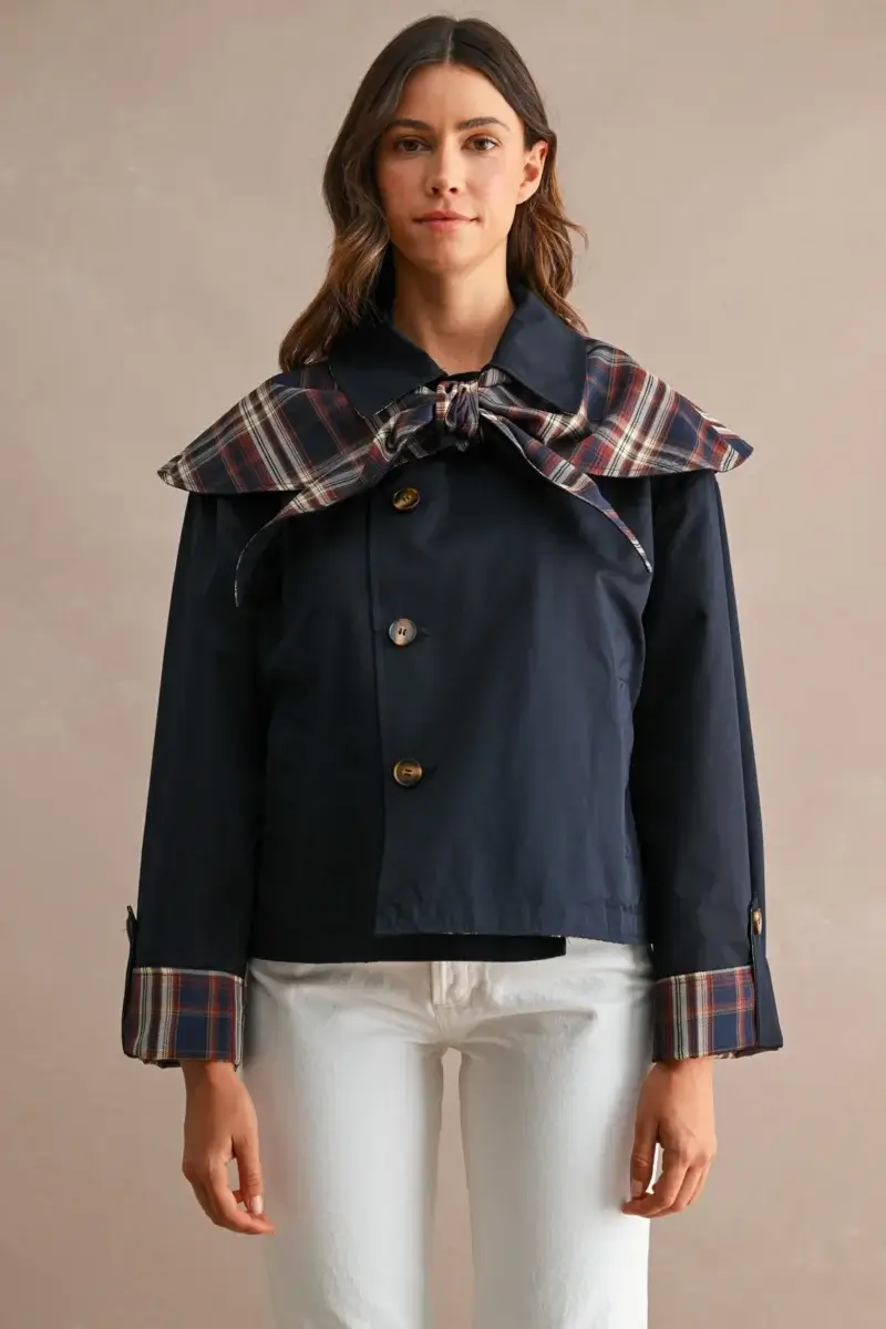 17 Fall-Ready Nashville FINDS: Cozy Layers, Beauty & Spooky Season Style - 4 Woman wearing a navy jacket with plaid collar and cuffs, white pants, standing against a plain beige background—a classic look inspired by Nashville finds this October.