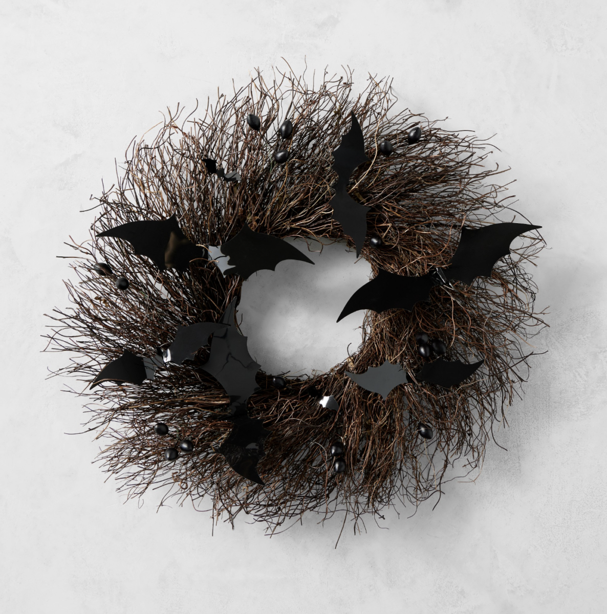 20 Halloween Decor FINDS That Are Actually Chic - 2 A wreath made of twigs is decorated with black artificial bats and small black berries, making it the perfect Halloween decor to add a festive touch to your space. Hung on a light gray wall, this piece embodies the spirit of spooky season and is sure to be one of your favorite Halloween finds.