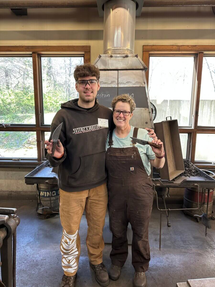 She's Making the Blind Feel Seen Through Louisville’s Newest Museum Experience - 5 Two people stand in a workshop, both smiling at the camera and holding knives. The background includes large windows and industrial equipment.