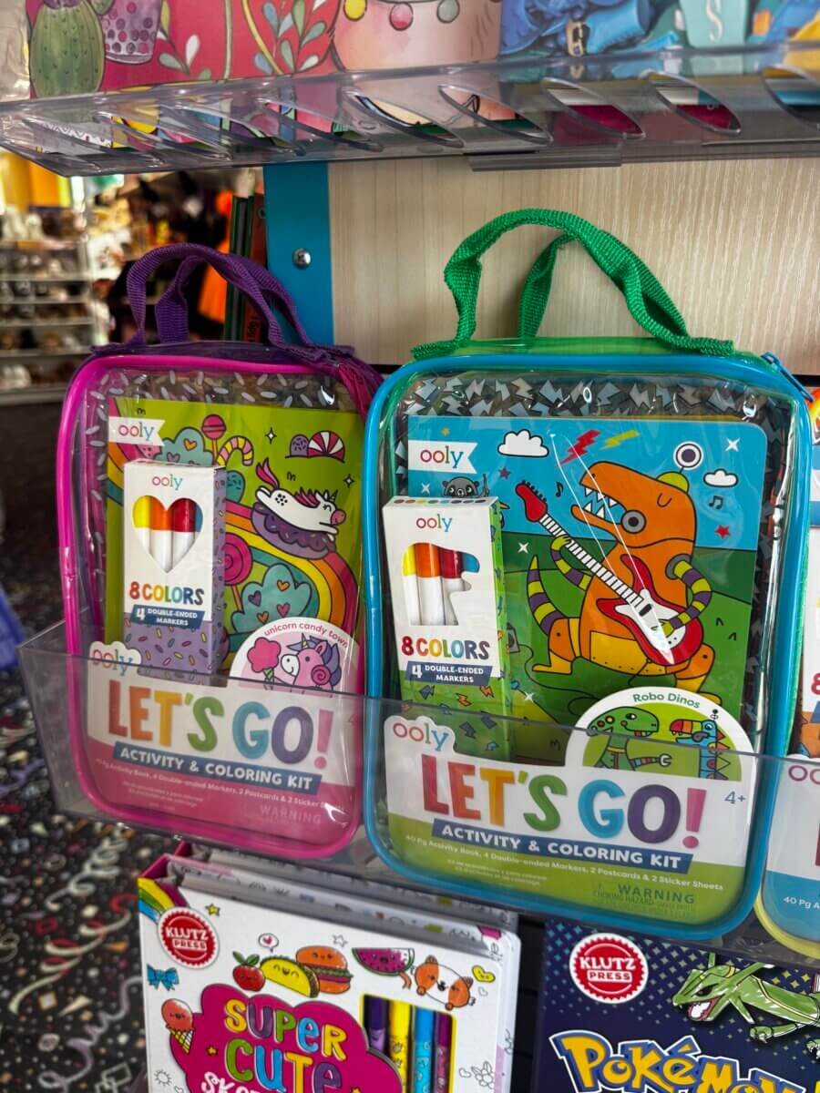 17 Louisville FINDS for October: Fall Fashion, Festive Decor & Game-Day Essentials - 17 Two “Let’s Go! Activity & Coloring Kit” packs—one with a pink handle and one with a green handle—hang on a store display above other kids’ activity books, making for perfect FINDS in Louisville this October.
