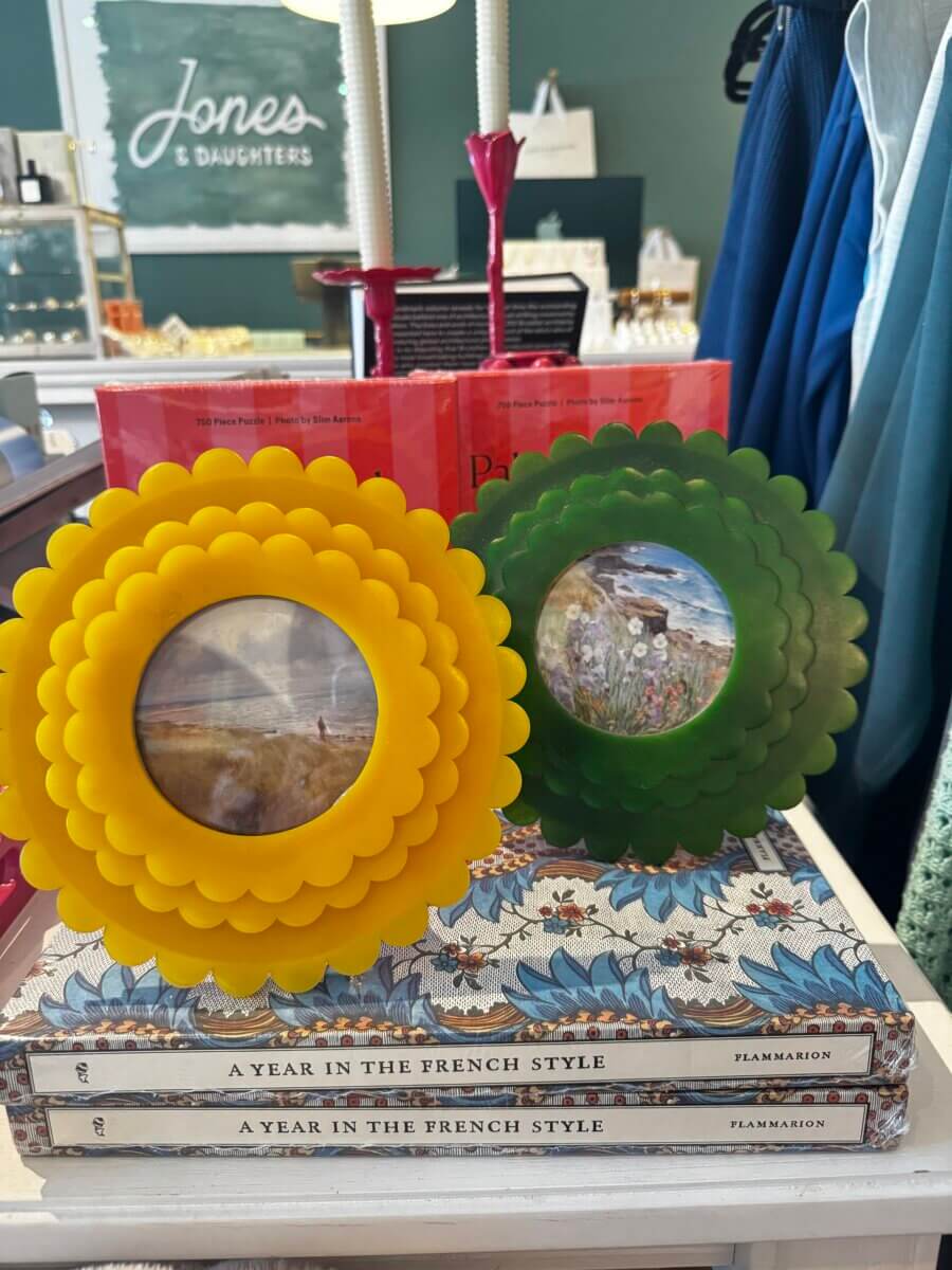 17 Louisville FINDS for October: Fall Fashion, Festive Decor & Game-Day Essentials - 15 Two floral-shaped picture frames, one yellow and one green, displayed on top of three stacked “A Year in the French Style” books in a boutique store setting, make for a charming October vignette featured by Louisville FINDS.