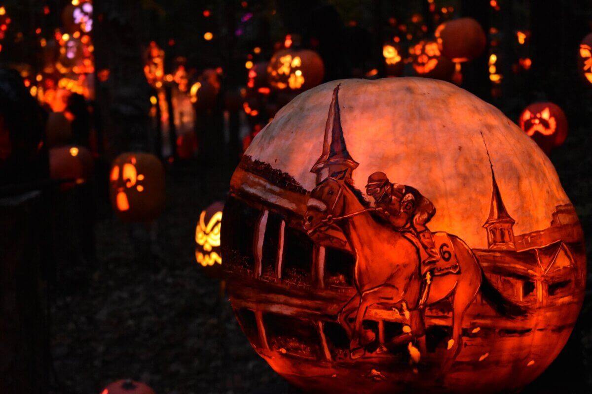 Photo: styleblueprint.com Large pumpkin intricately carved with a horse racing scene, surrounded by other glowing carved pumpkins at night