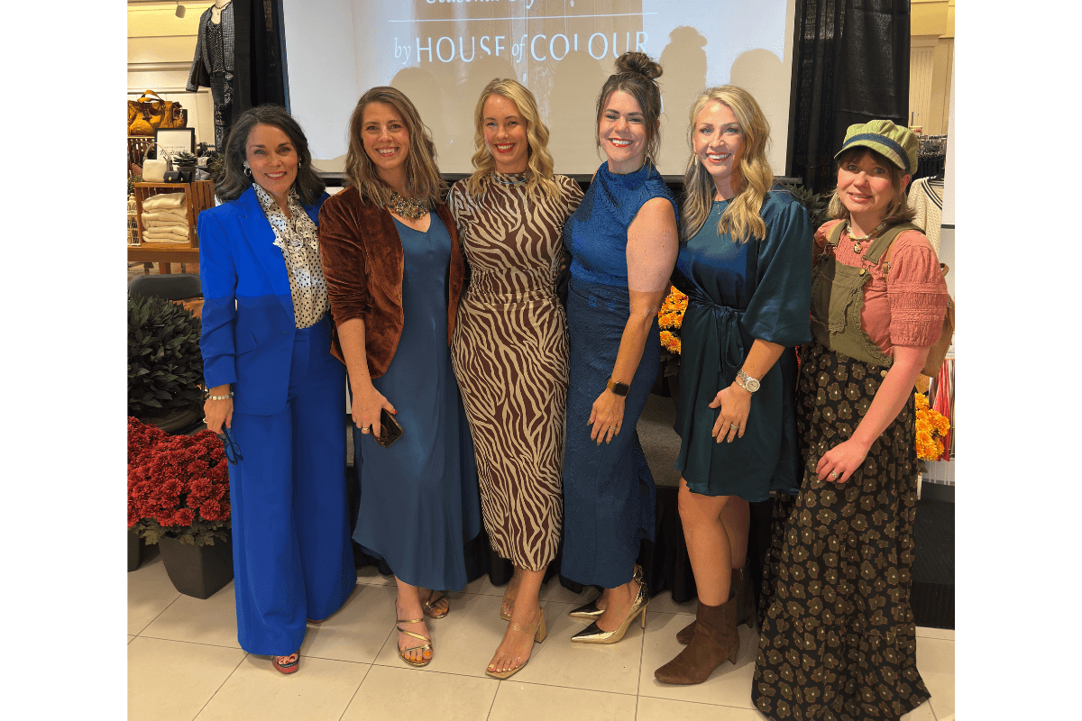 Louisville Fall Fashion 2026: 3 Runway Trends to Incorporate - 7 Six women pose together indoors at an event, standing before a “House of Colour” display, showcasing the latest Fall Fashion 2026 runway trends.