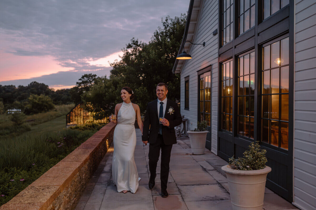 18 Guests + One Gorgeous Louisville Greenhouse Wedding - 13 A bride and groom walk with cocktails in their hands.