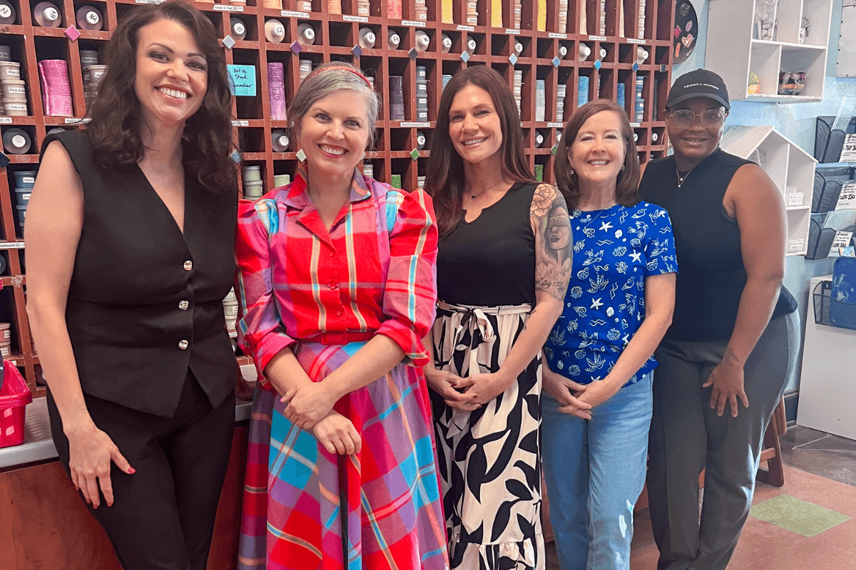 Create, Connect & Get a Little Messy at This Memphis Pottery Studio - 5 Five women stand smiling in front of a wall of hair color products in a salon, wearing a mix of colorful and patterned outfits.
