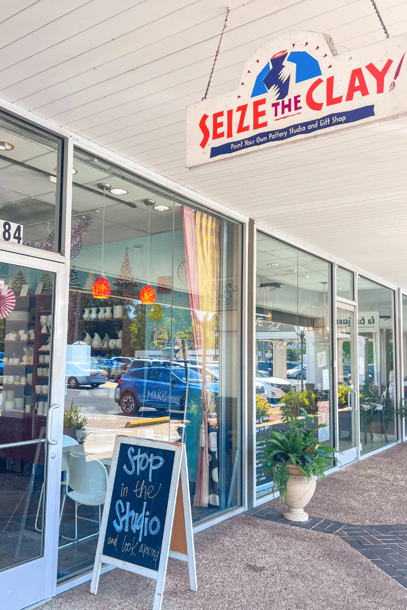 Create, Connect & Get a Little Messy at This Memphis Pottery Studio - 6 A storefront with a sign reading “Seize The Clay,” large windows displaying pottery, and a sidewalk chalkboard inviting people to visit the studio.