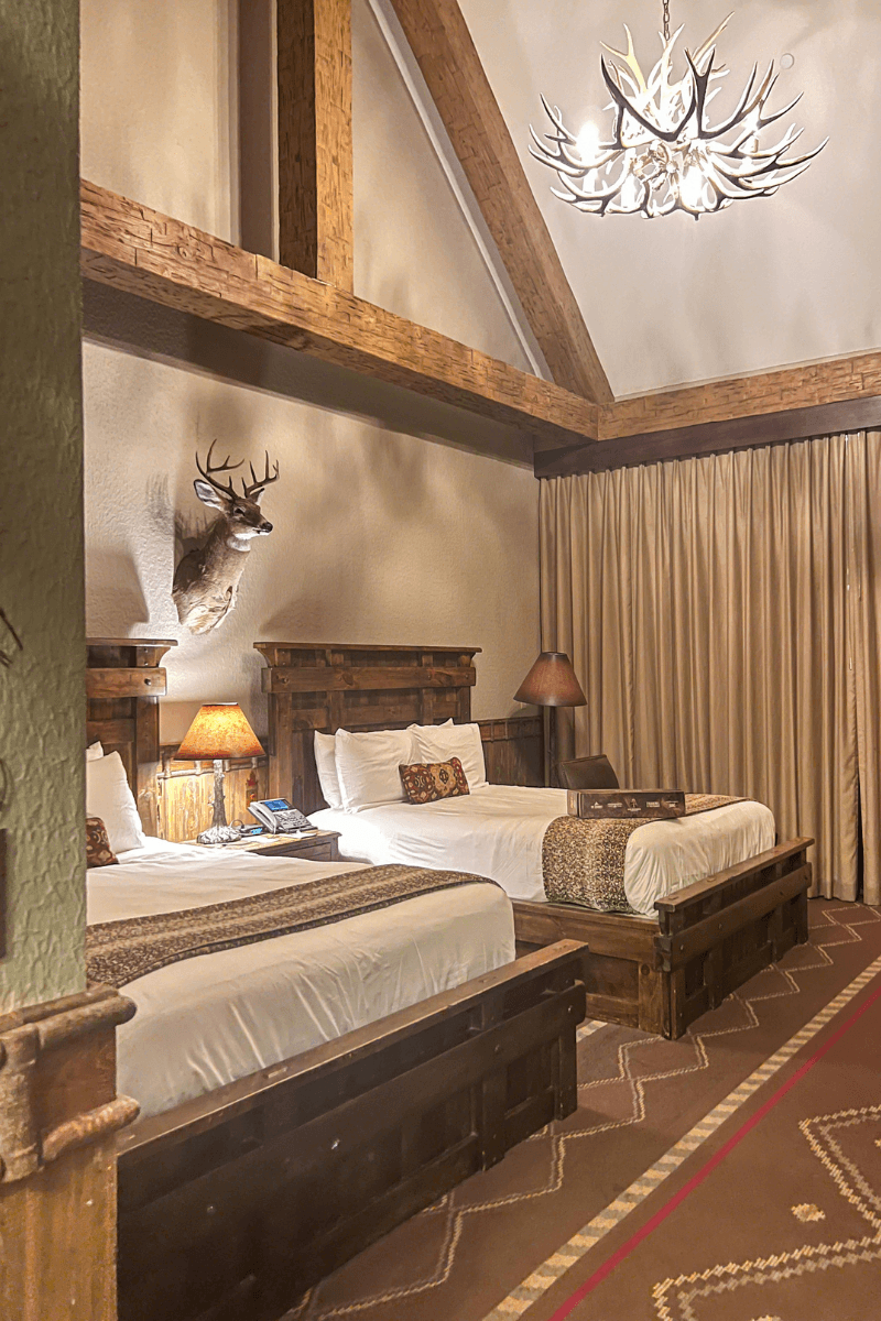 Did You Know You Could Spend the Night in the Memphis Pyramid? - 8 Hotel room with two beds, wooden furniture, a mounted deer head on the wall, beige curtains, and an antler chandelier on the ceiling.