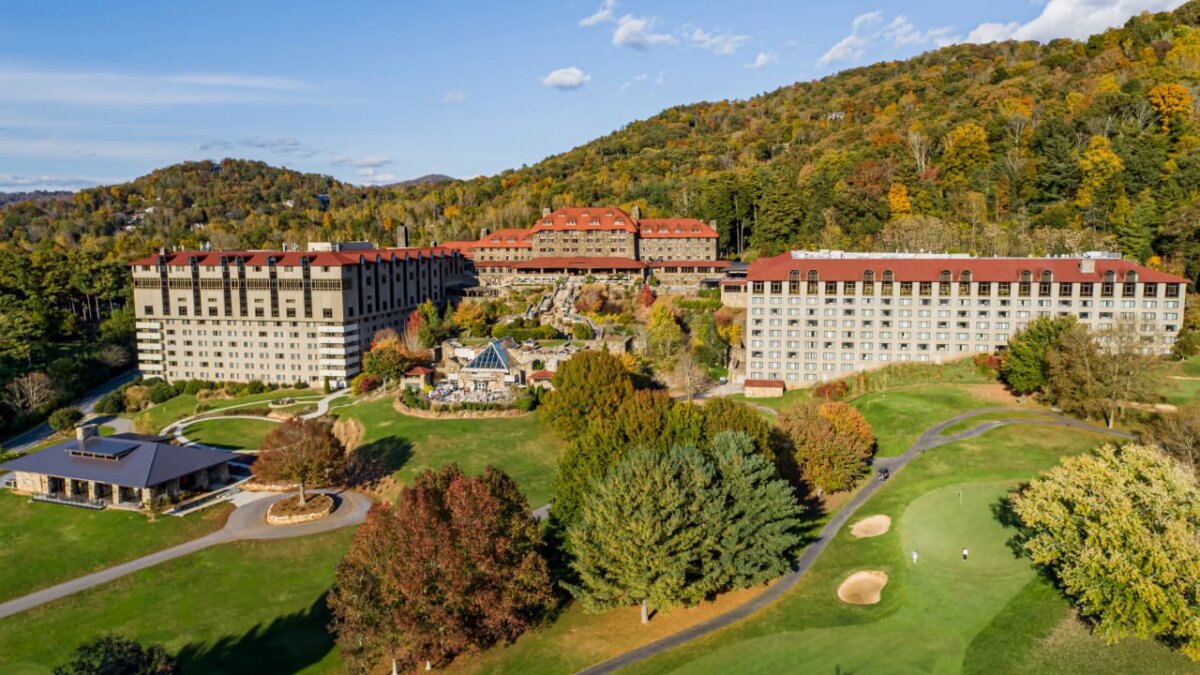 A large resort complex with red roofs sits among trees and hills in autumn, bordered by a golf course with sand bunkers and putting greens. Known as one of the South’s most haunted hotels, this storied retreat combines natural beauty with mysterious tales whispered among the falling leaves.