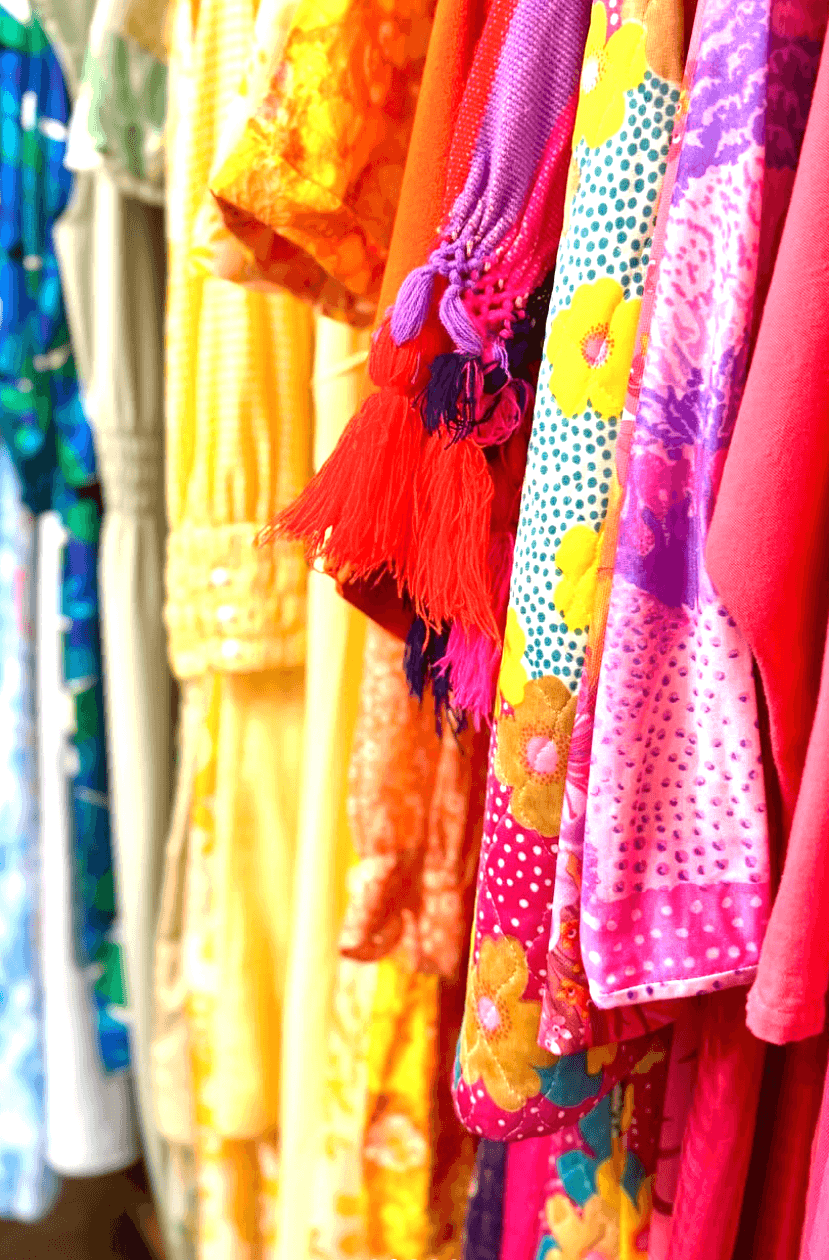 Your Guide to Antiquing in Memphis: 10 Shops Worth Exploring - 6 A rack of colorful dresses in various floral and patterned designs, arranged in a gradient from yellow to pink.