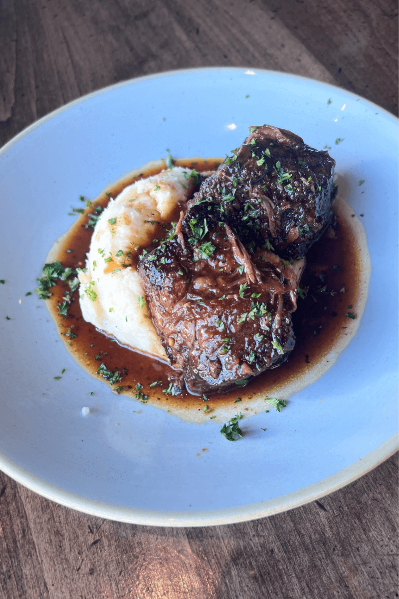 Did You Know You Could Spend the Night in the Memphis Pyramid? - 7 Braised beef short ribs with brown sauce served beside a mound of mashed potatoes, garnished with chopped herbs on a white plate.