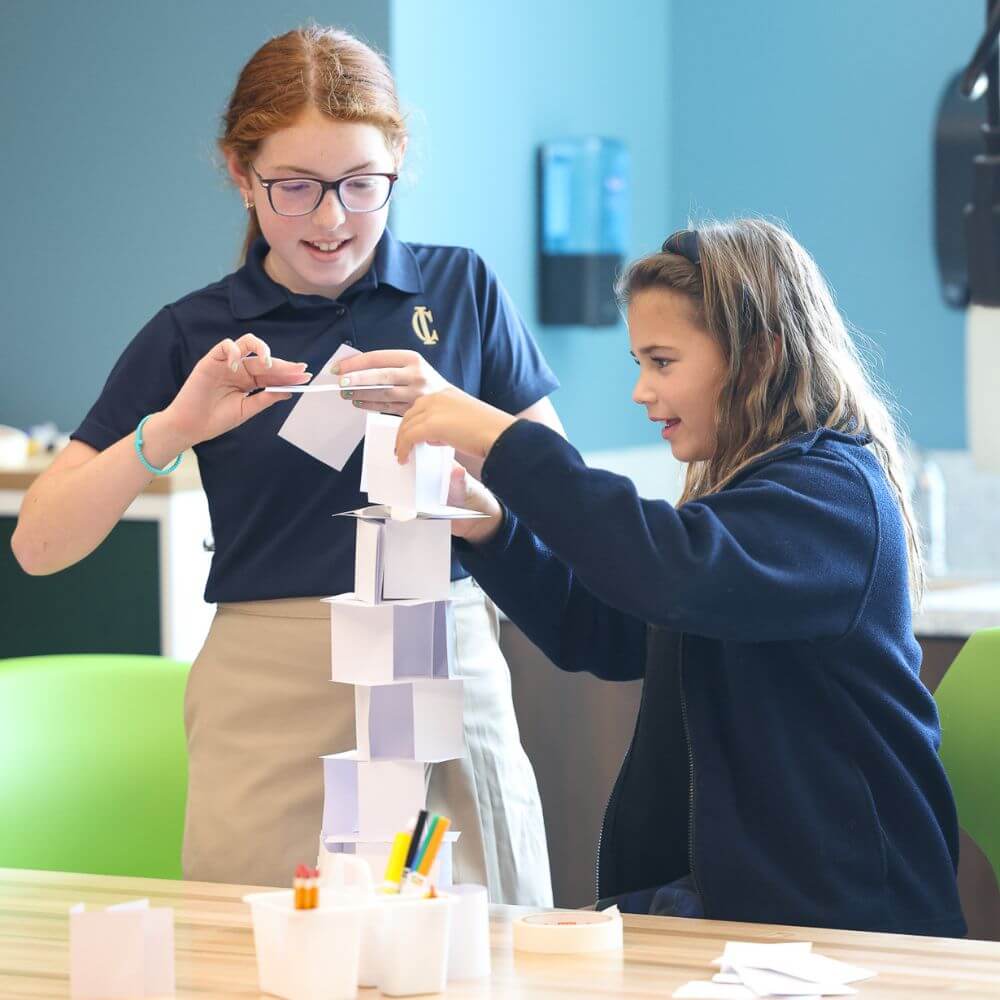 This Nashville School Is Giving Students More Room to Explore, Create & Build - 3 Two girls at a Nashville school build a tall structure from paper squares at a table in a classroom, with pencils and containers nearby.