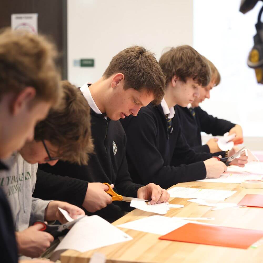 This Nashville School Is Giving Students More Room to Explore, Create & Build - 4 A group of students at a Nashville school sit at a wooden table, focused on cutting paper with scissors during a classroom activity designed to support learning differences.