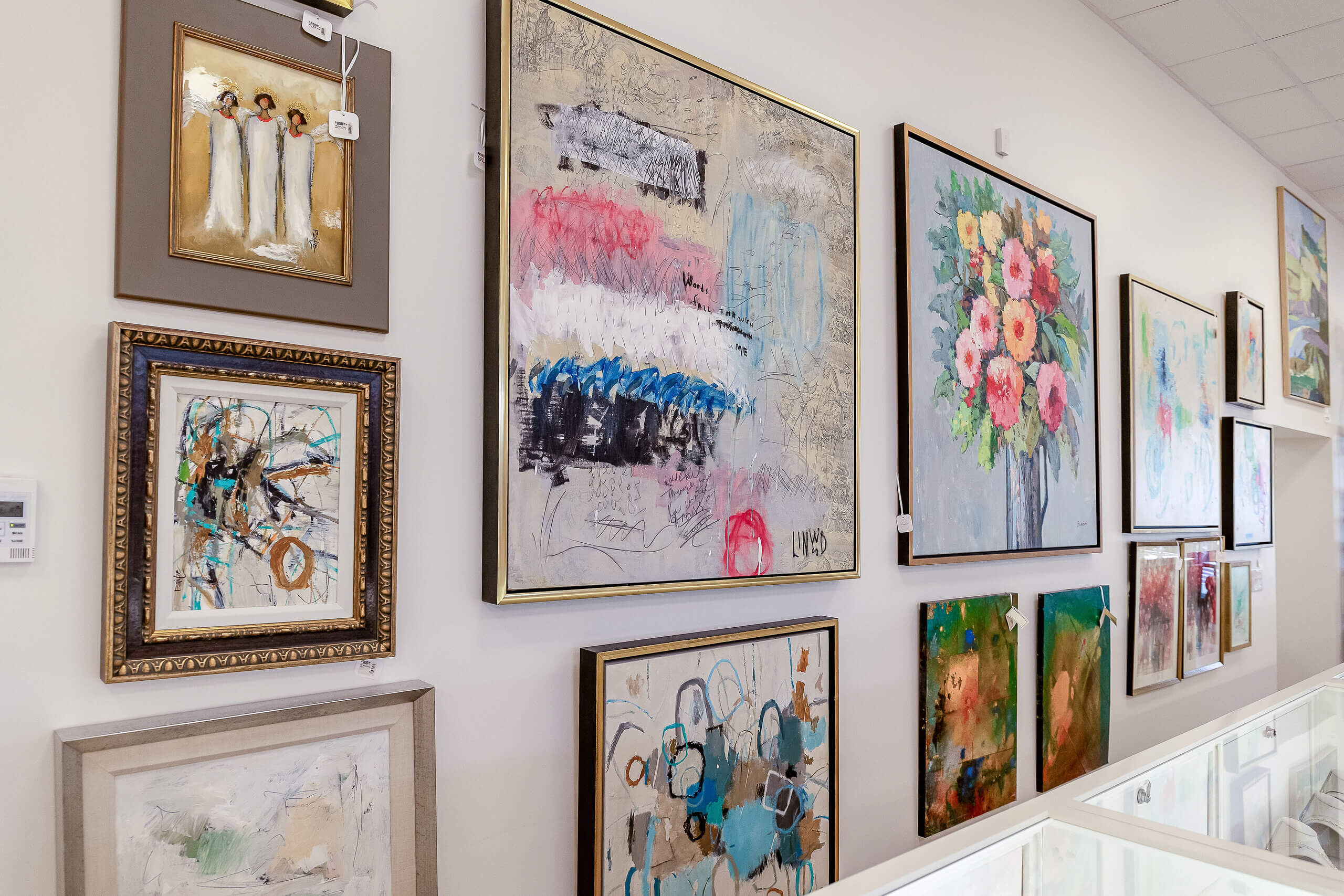 A gallery wall of abstract and floral paintings, perfect for interior design gifts.