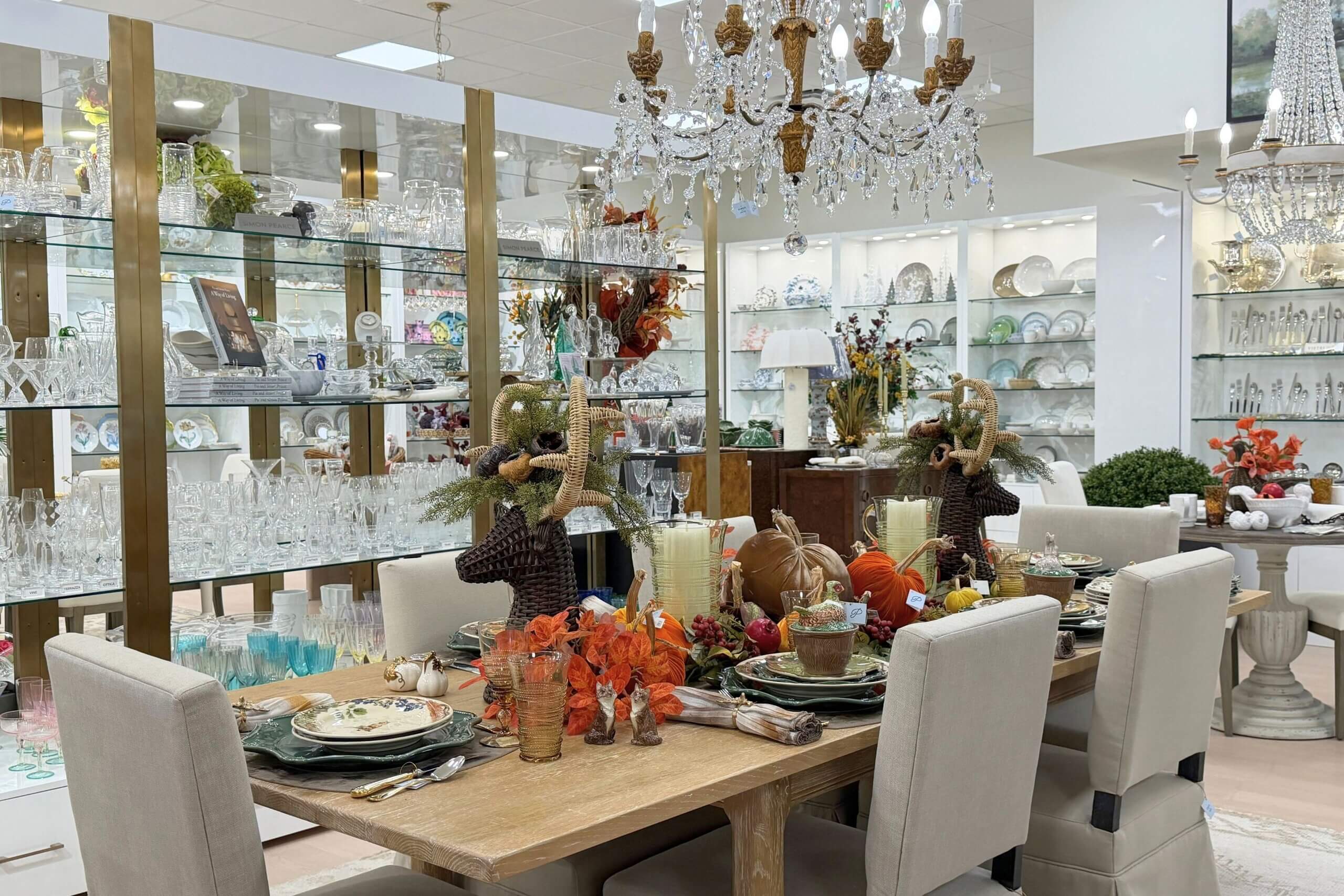 Thanksgiving dining table set with deer-shaped centerpieces, pumpkins, seasonal foliage, and place settings, displayed as home interiors.