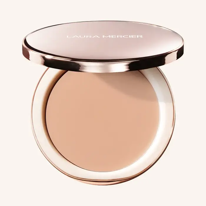 An open compact of Laura Mercier pressed powder foundation with a beige shade, shown on a neutral background.