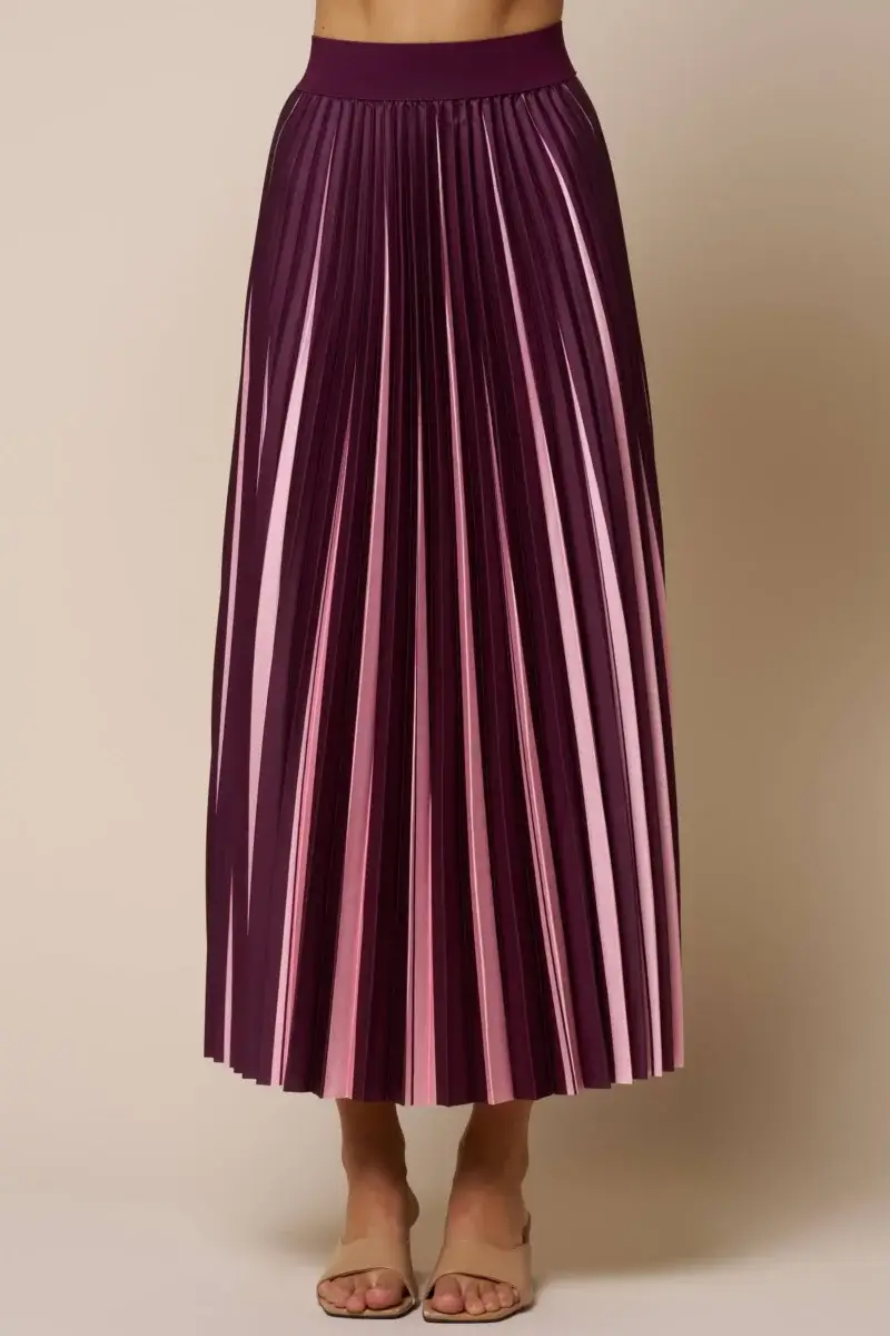A person wearing a high-waisted, pleated skirt with alternating dark purple and pink vertical stripes, paired with open-toe beige sandals.