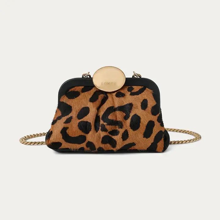 A chic FINDS discovery, this small leopard print handbag features a gold chain strap and a round gold clasp on top, photographed against a plain background—perfect for turning heads during stylish September outings in Nashville.