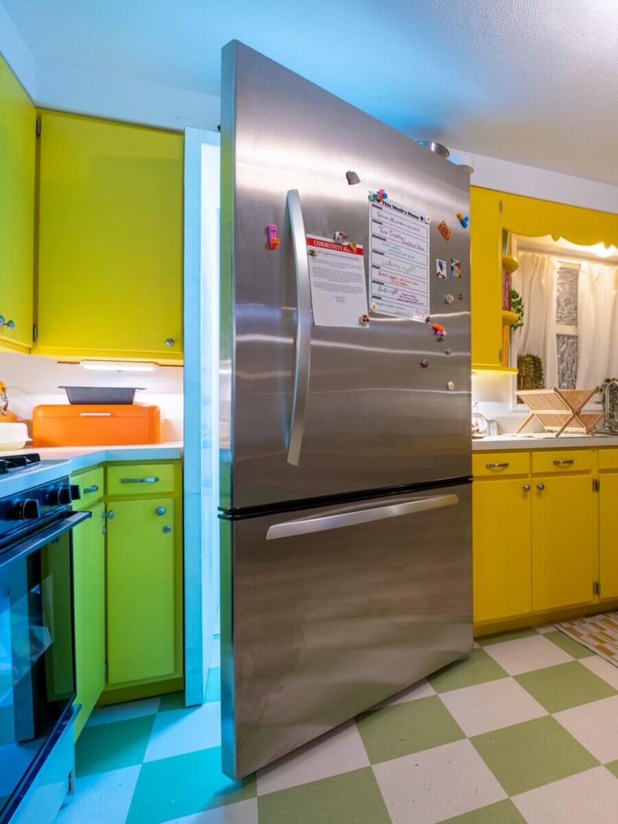 7 Southern Art Museums & Installations Worth Planning a Trip Around - 8 A stainless steel refrigerator stands slightly open in a retro-style kitchen, revealing a glowing passageway at a Meow Wolf Art Installation.