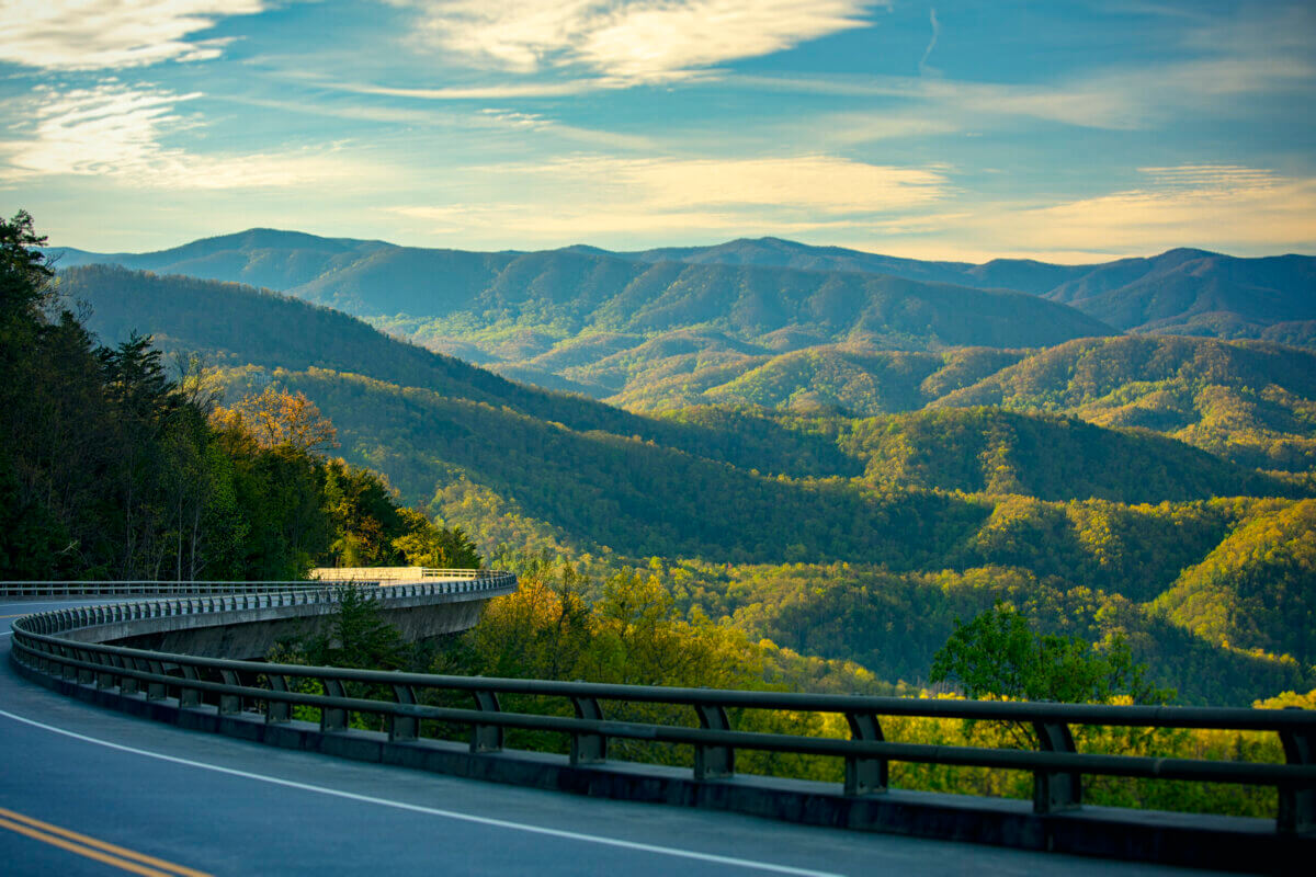 For the Love of Dolly: 7 Ways to Celebrate Her Legacy - 9 Curving mountain road with a guardrail overlooking rolling, forested hills of the Great Smoky Mountains.