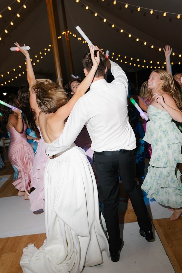 A Nashville Bride's Beautiful Tribute to Her Late Dad Only Made the Wedding More Joyful - 18 A bride and groom dance together under string lights at a beautiful Garden-Party Wedding at Ravenswood Mansion in Brentwood, surrounded by guests in colorful dresses also dancing and celebrating.
