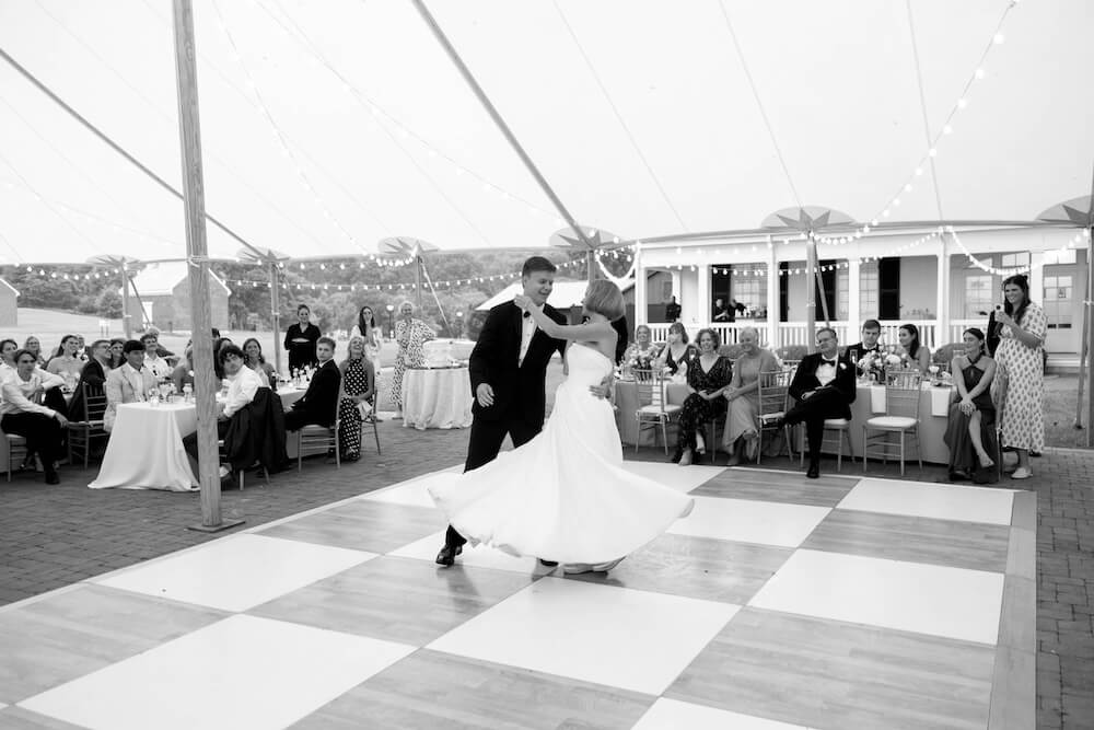 A Nashville Bride's Beautiful Tribute to Her Late Dad Only Made the Wedding More Joyful - 15 A bride and groom dance on a checkered floor under a tent while guests watch from tables at their garden-party wedding at Ravenswood Mansion in Brentwood.