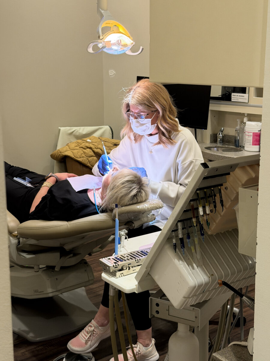 Healthy Smiles for Life: A Guide to Family Dental Care For Every Age - 8 A dental professional wearing a mask examines a patient’s teeth in a dental clinic, ensuring family dental care and promoting healthy smiles. Dental tools and equipment are visible in the foreground.