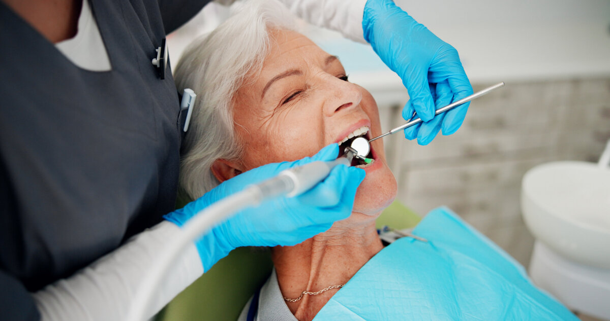 Healthy Smiles for Life: A Guide to Family Dental Care For Every Age - 9 Older woman receiving a dental checkup; dentist wearing gloves uses dental tools to examine her mouth in a clinic setting, emphasizing family dental care for healthy smiles at every age.