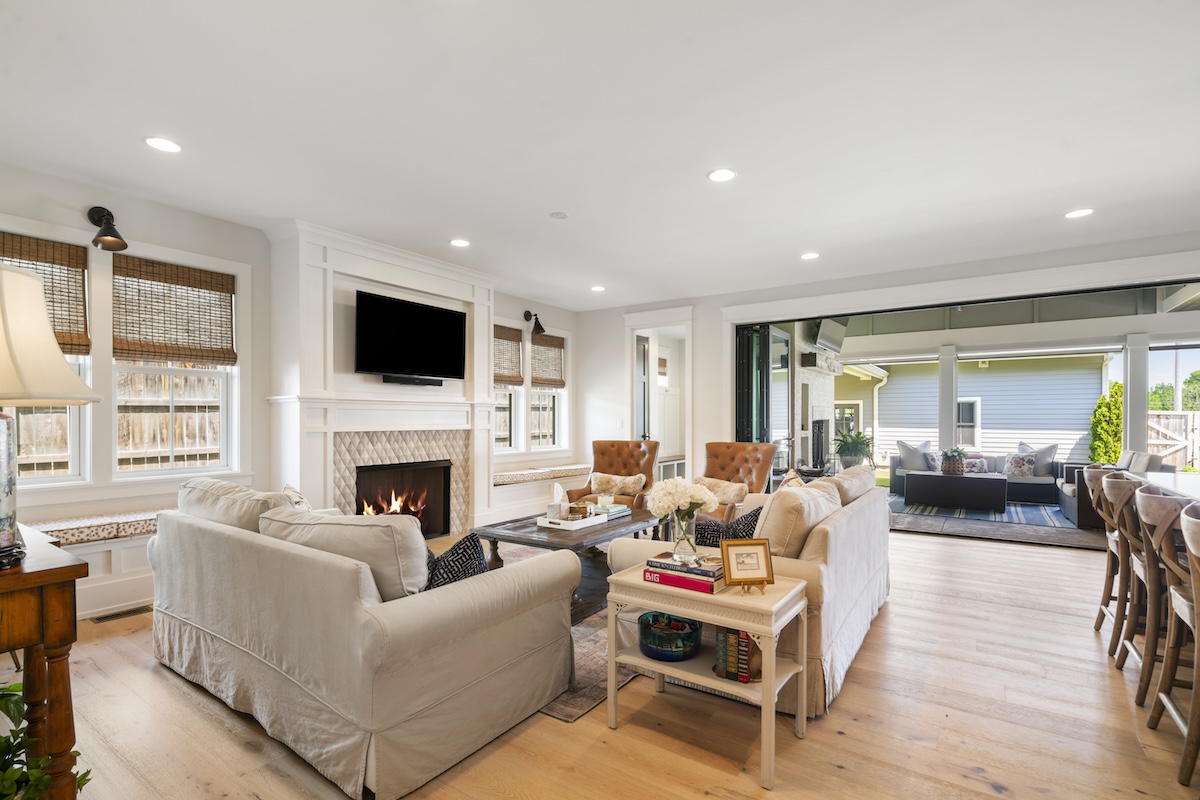Living room with a fireplace, television, two sofas, and a view into a covered outdoor patio.