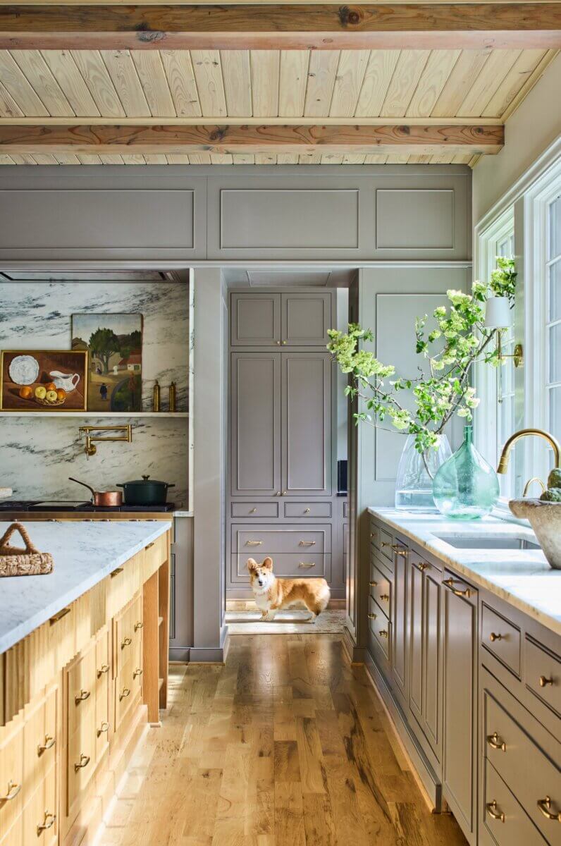 Your Home Should Tell Your Story — and Leigh Misso Wants to Help You Write It - 12 A Corgi stands in the doorway of a kitchen featuring building-informed design, grey cabinets, marble countertops, and wooden accents.