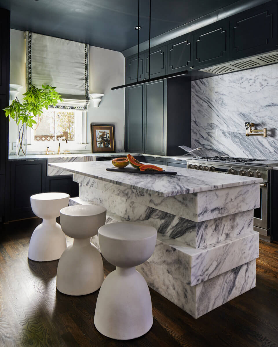 Your Home Should Tell Your Story — and Leigh Misso Wants to Help You Write It - 16 Kitchen island with a thick marble base and countertop, paired with three sculptural white stools, featuring halved papayas on a cutting board in this custom home design by River Brook Design.