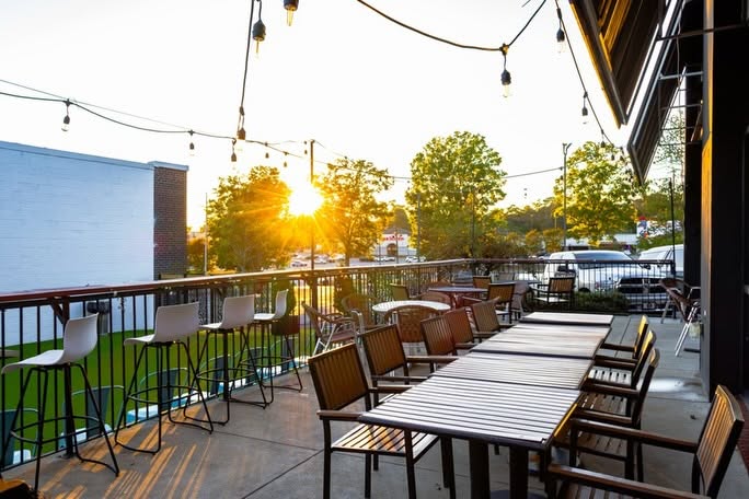 5 New Birmingham Restaurants to Try This Month (Plus An Expansion & A Relocation!) - 7 Outdoor restaurant patio with high-top bar stools and dining tables at sunset.