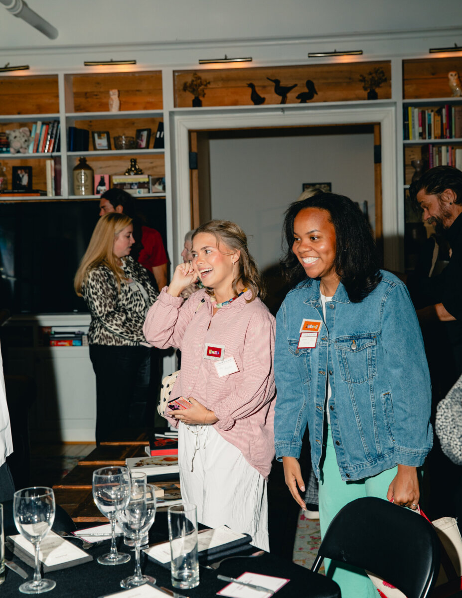 What Happens When You Bring 22 Birmingham Strangers Together and Say "Trust Me"? - 2 Two smiling women wearing name tags at a Birmingham Trust Me Night social gathering, standing near a table with glassware.