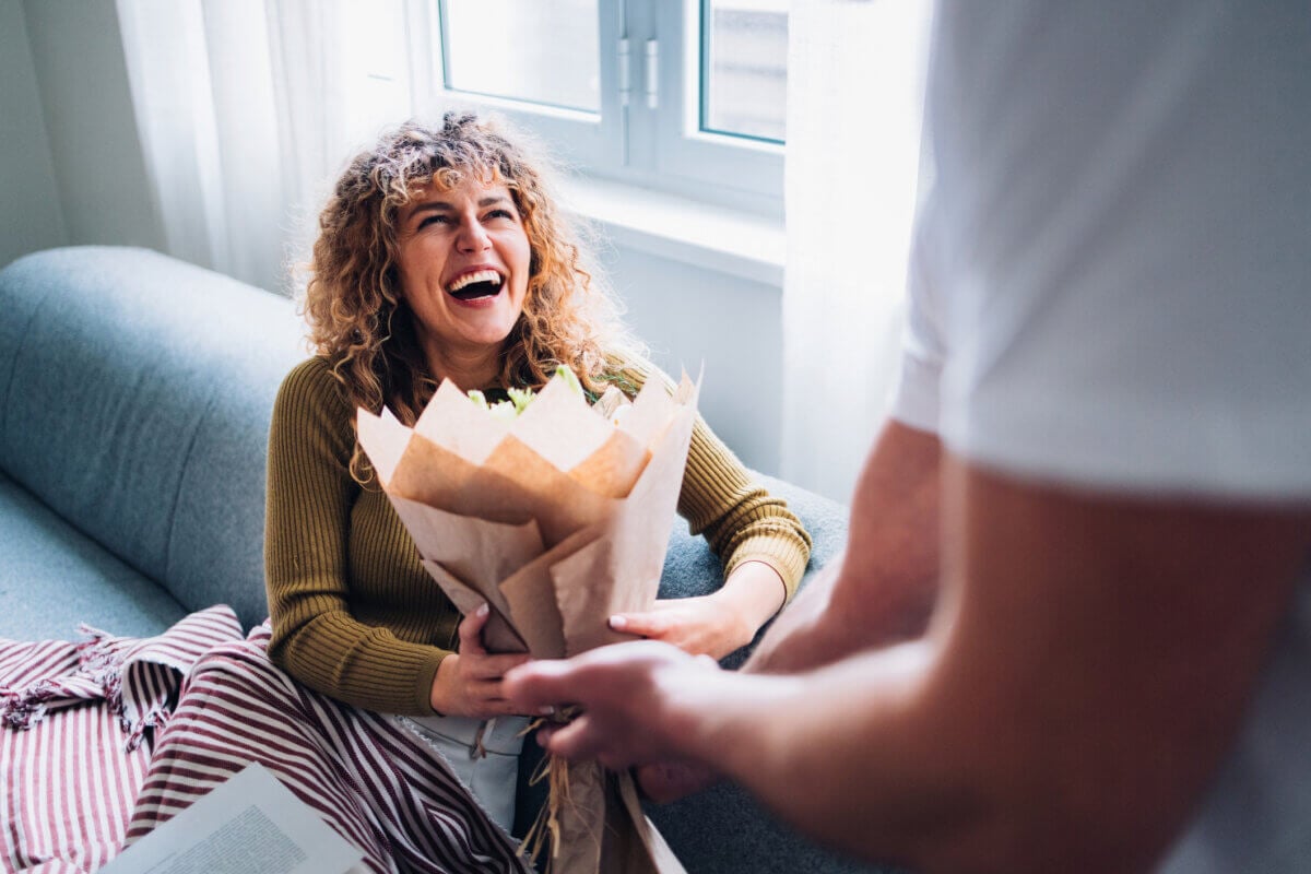 How Not to Date a Loser: Therapists Share the Red Flags You Shouldn't Ignore - 3 A woman laughing as she receives a bouquet of flowers, a gesture often discussed in dating advice.
