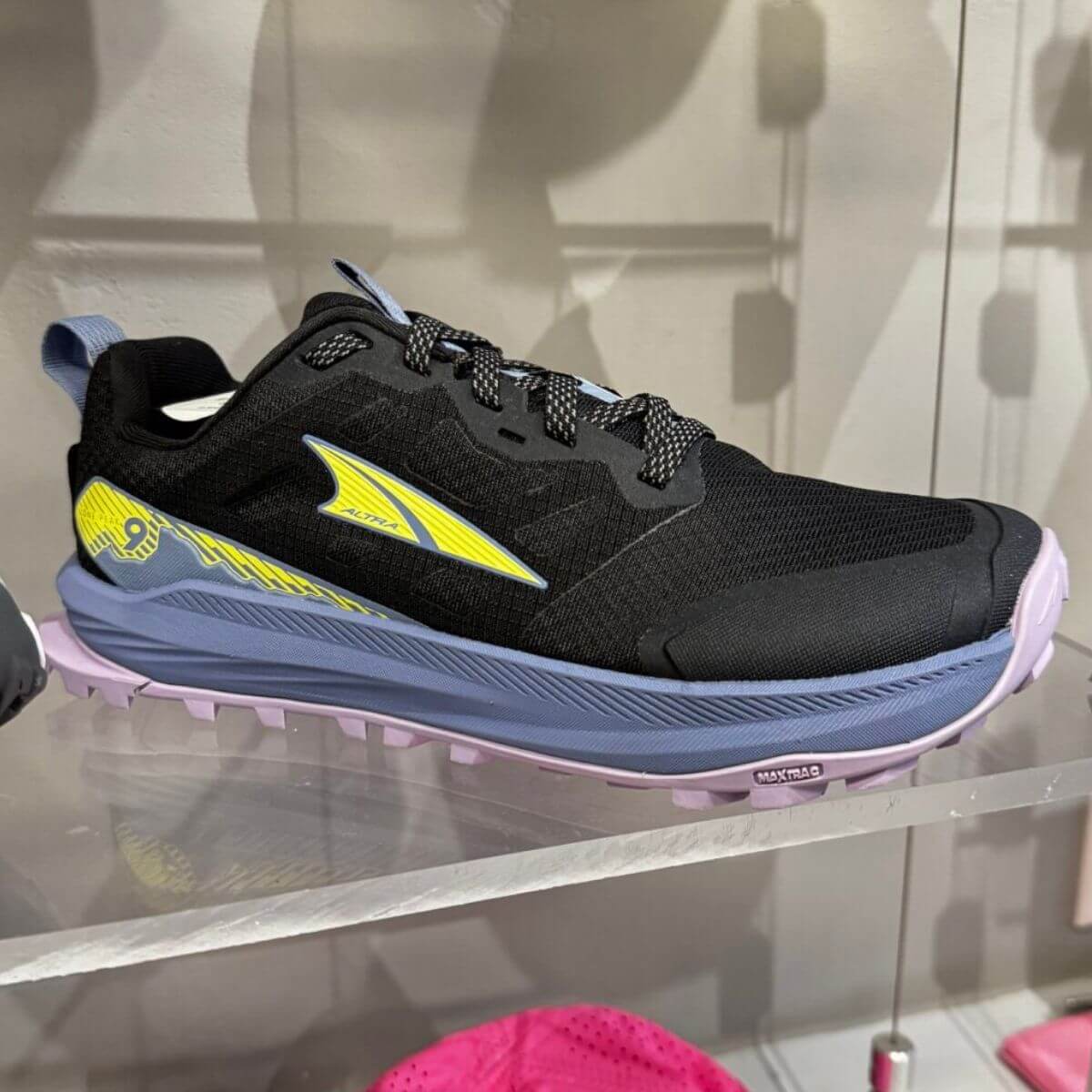 17 Louisville FINDS for October: Fall Fashion, Festive Decor & Game-Day Essentials - 5 A black, blue, and yellow athletic shoe with a purple sole—one of the exciting Louisville finds this October—displayed on a glass shelf against a light-colored wall.
