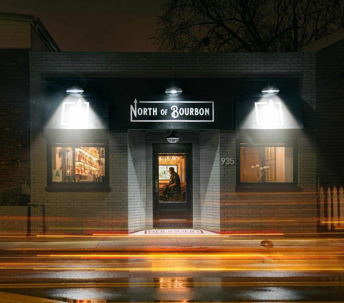 Exterior of North of Bourbon restaurant at night with light streaks on the street.