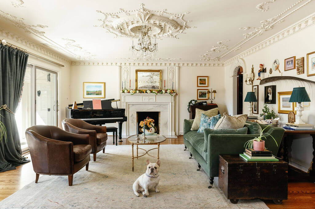 From ICU Nurse to Interior Designer: Meet Gretchen Rose of Kentucky Rose Designs - 11 A French bulldog sits in a living room designed by Gretchen Rose, featuring a green sofa, two brown leather armchairs, a grand piano, and an ornate fireplace.