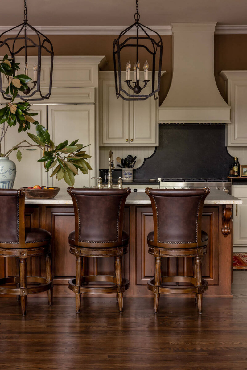 From ICU Nurse to Interior Designer: Meet Gretchen Rose of Kentucky Rose Designs - 13 Kitchen island with three brown leather bar stools, designed by Gretchen Rose, facing a range, cabinets, and two metal pendant lights.